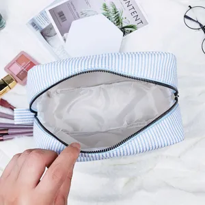 Detailansicht einer hellblau gestreiften Seersucker-Kosmetiktasche mit praktischen Innentaschen
