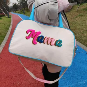 Detailed macro view of the Mama embroidery on a large white nylon travel handbag