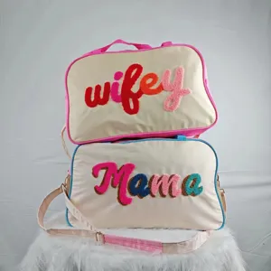 Close-up of large travel bags with colorful 'Wifey' and 'Mama' chenille embroidery