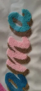 Close-up of high-quality colorful bouclé embroidery detail on a minimalist travel bag