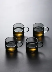 Close-up of four smoky gray heat-resistant glass tea cups with handles on dark table