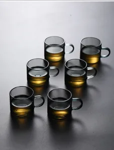 Detailed top view of six smoky grey heat-resistant glass tea cups with handles on dark surface