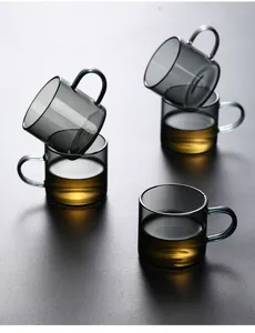 Stack of smoky gray heat-resistant glass tea cups with elegant handles on dark surface