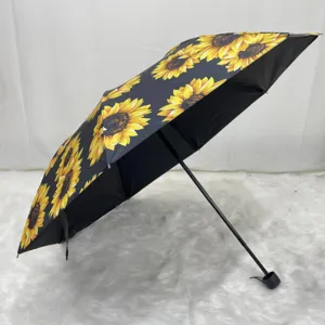 Close-up of vibrant sunflower print on black UV-protective folding umbrella fabric