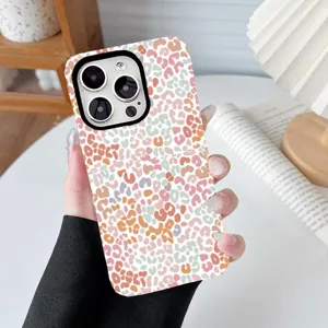 Detailed view of colorful leopard print phone case held in hand on white desk.
