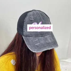 Close-up of a distressed grey mesh baseball cap with personalized purple embroidery detail