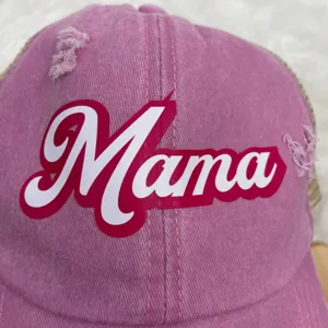 Close-up view of the white Mama script logo and distressed details on a pink baseball cap.