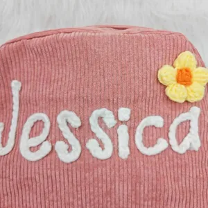 Close-up detail of custom name Jessica embroidered on pink corduroy fabric backpack