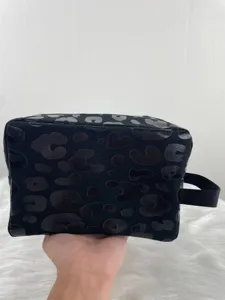 Detailed macro view of large leopard print toiletry bag with black nylon handle strap