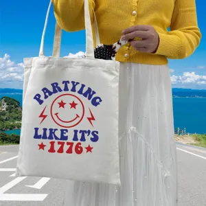 Detail view of a white canvas tote bag with the 1776 Independence Day smiley print