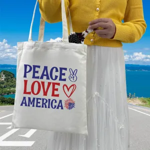 Woman holding an Independence Day canvas tote bag with Peace Love America print.