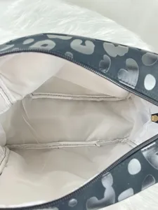 Interior view of leopard print cosmetic bag showing spacious white lining and zipper