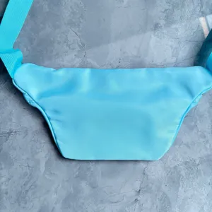 Detail view showing the back side of a cyan travel fanny pack with durable nylon texture