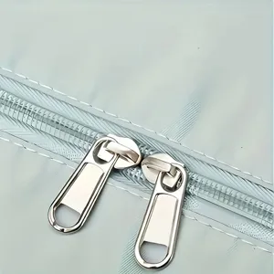 Macro detail of high-quality double metal zippers on a light blue sports bag