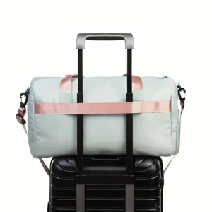 Mint green weekend travel bag with rose gold straps on a suitcase handle