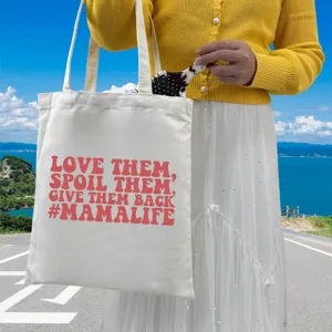 Detailed view of cream canvas tote bag featuring red #MAMALIFE printed slogan design