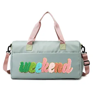 Close-up of a light green duffle bag with colorful 'weekend' chenille embroidery.
