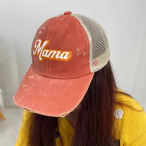 Close-up detail of distressed orange mesh baseball cap featuring Mama print design