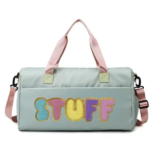 Close-up of mint green duffel bag with colorful STUFF chenille patches and gold borders
