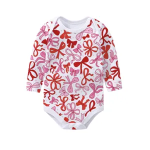 Long-sleeve infant bodysuit in white featuring stylized red and pink bow patterns
