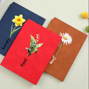 Elegant detail of A5 soft leather notebooks with custom floral prints and names