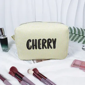 Gelb gestreifte Seersucker-Kosmetiktasche mit CHERRY-Stickerei auf weißem Hintergrund