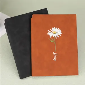 Detailed view of A5 soft leather notebook featuring a white daisy flower and text design