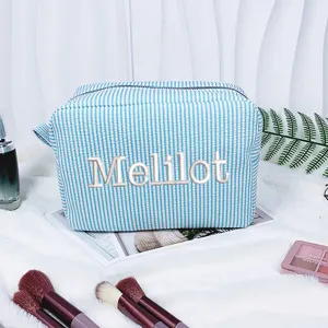 Detailansicht einer blau gestreiften Seersucker-Kosmetiktasche mit weißer Bestickung