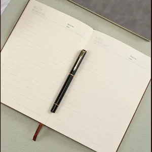 Macro view of open A5 business journal with black fountain pen on lined cream pages