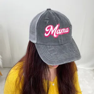 Close-up of distressed gray mesh trucker hat with pink Mama embroidery worn by model