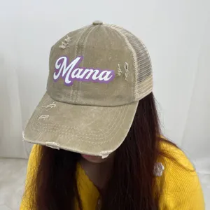 Detailed view of the distressed khaki ponytail trucker hat featuring a purple Mama print