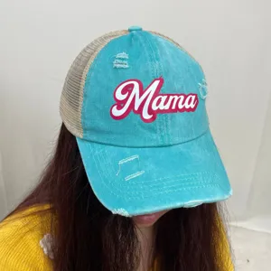 Detail view of a blue distressed denim trucker hat with Mama print worn by a model.