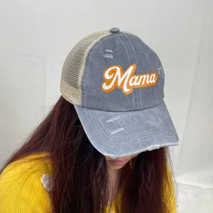 Detail view of washed gray distressed trucker hat with orange Mama print worn by model