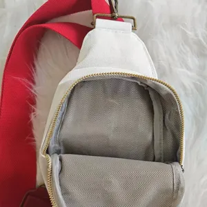 Detailed macro view of white canvas sling bag showing herringbone interior and red strap