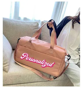 Close-up of a large pink sports gym bag featuring personalized text on a cozy sofa