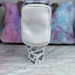 Detail view of a white neoprene pouch attached to a 40oz tumbler with cow print