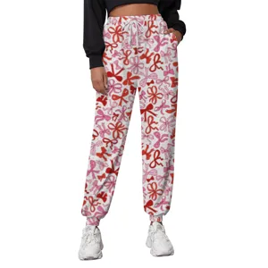 Close-up of women's white sweatpants with red bow patterns, elastic drawstring waist details.