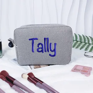 Detailansicht einer gestreiften Seersucker-Kosmetiktasche mit blauem Sticknamen Tally