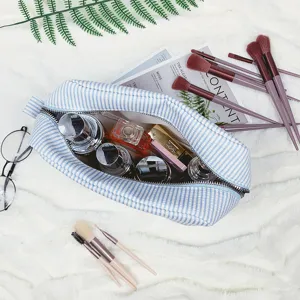 Detailansicht der gestreiften Seersucker-Kosmetiktasche mit Make-up und Pinseln.