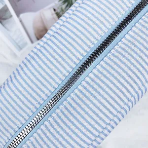 Detailaufnahme des Metallreißverschlusses und des blau gestreiften Seersucker-Stoffs