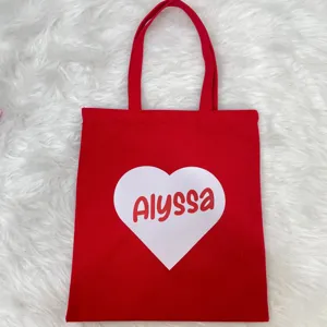 Close-up of a vibrant red canvas tote bag featuring a white heart with custom name Alyssa