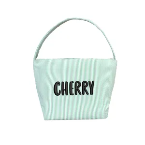 Macro view of green seersucker Easter bucket with custom black embroidered name Cherry