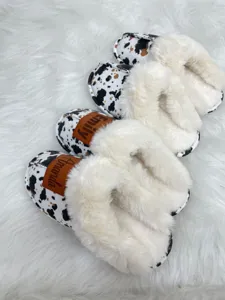 Close-up of cozy cow print slippers with personalized name patches and faux fur