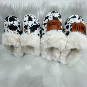 Close-up of customized cow print slippers with plush faux fur and name patches