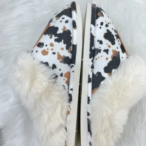 Close-up detail of Western-style cow print furry slippers with soft plush lining