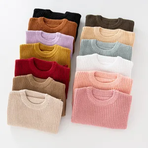 Overhead view of solid color crewneck knit sweaters for girls in a variety of vibrant tones