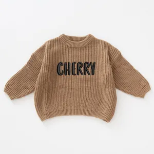 Detail view of brown knitted girls' sweater with 'CHERRY' embroidery and round neck