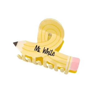 Close-up of a yellow pencil-shaped hair claw clip with custom name engraving