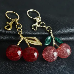 Vue détaillée de deux porte-clés cerises créatifs avec fruits pailletés et tiges dorées