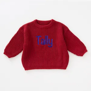 Detailed macro view of red knitted children's sweater with blue embroidered Tally text